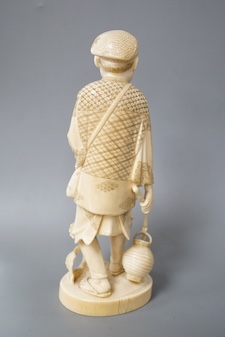 A Japanese carved ivory figure of a farmer, Meiji period, c.1900, signed, carrying a lantern on a stick, maize grows at his feet, a toad climbs on one arm, height 20.5cm